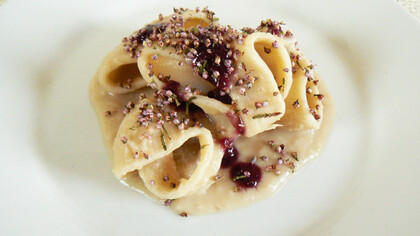 Conchiglioni di pasta con crema di cannellini guarniti con salsa agrodolce di uva nera e fiori essiccati di erica