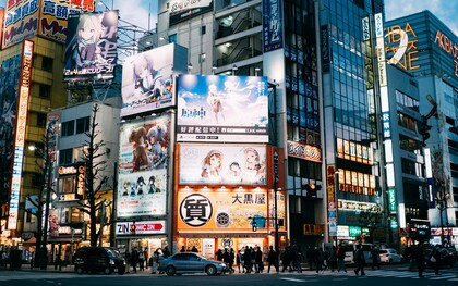A bustling Tokyo district surrounded by towering anime billboards and media advertisements, symbolising the cultural prominence anime and manga have achieved in Japan and beyond