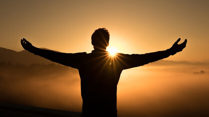 The essence of success with a stunning silhouette photo featuring a man on a cliff during a breathtaking sunset