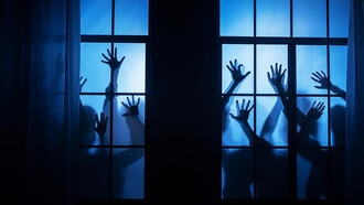 Spooky zombie hands pressing against a windowpane in the dead of night