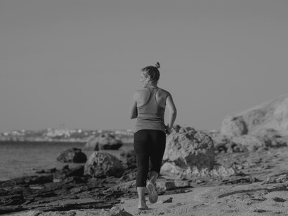 As a woman takes her jog on the beach, she looks over to the ocean