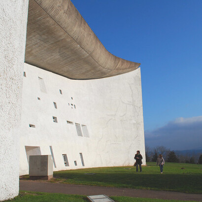 The sweeping curves of Notre Dame du Haut's roof, symbolizing maternal protection and shelter, stand as a masterpiece of modern architecture, Ronchamp, France