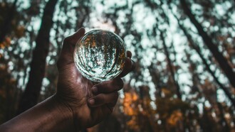 Mão segura uma esfera de vidro que reflete a floresta ao redor. A sustentabilidade tornou-se um dos principais indicadores de credibilidade e valor nos mercados de capitais contemporâneos. O equilíbrio entre crescimento econômico, transparência e responsabilidade ambiental está no centro das discussões sobre ESG. O futuro do investimento global passa cada vez mais pela integração de critérios sustentáveis e práticas de governança. Em mercados emergentes como Moçambique, sustentabilidade e confiança institucional caminham lado a lado. A pressão internacional por relatórios ambientais e sociais redefine a relação entre empresas e investidores