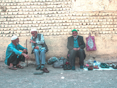 Tres migrantes afganos sentados en la calle en la Provincia de Qom, Irán 