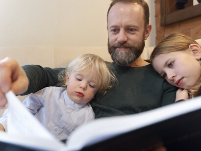 Esta semana tengo a las niñas. Bien. Pero una rabia resurge. Padre leyendo un libro con sus hijas