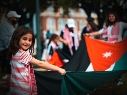 Una niña sonríe mientras hondea la bandera de Palestina