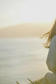 Una mujer sentada en un muelle, conectando con todo lo que la rodea