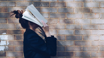 Mulher com livro no rosto. Somos contadores de histórias na nossa própria mente em forma de monólogo