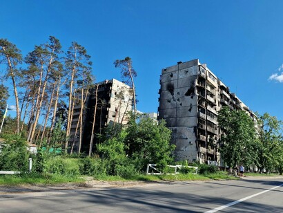 A destroyed housing complex in Ukraine lined with surviving trees, reflecting the tension between life and destruction