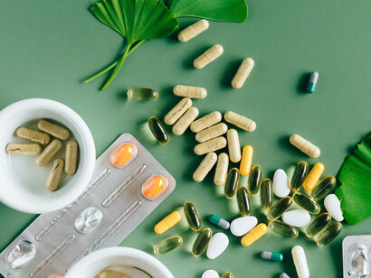 Multivitamins and herbal elements rest on a green table, capturing the intersection of natural remedies and nutritional supplements