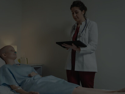 A cancer patient, a woman, lies in a hospital bed adorned in a gown, her resilience evident in the face of chemotherapy