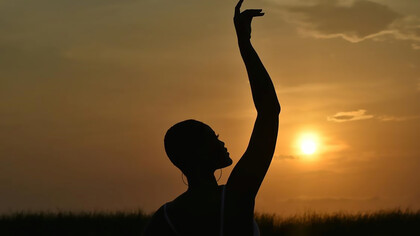 As the sun dips below the horizon in Accra, located in the picturesque Greater Accra Region of Ghana, the warm hues of the sunset illuminate the scene, casting a captivating glow on a woman immersed in the tranquil beauty of the moment