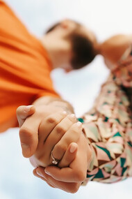 Joyful young couple dressed in vibrant clothing, posing against a bright sky backdrop
