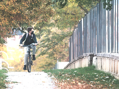 Un chico en bicicleta mira atentamente hacia el otro lado de la verja