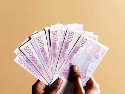 A man showing sheets of euro bills in his hand to show his determined position in the European network economy