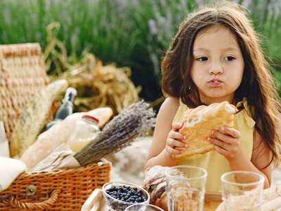 A young girl at a picnic, learning about the Zero Waste lifestyle and contributing to the Zero Hunger Initiative by sharing meals made from leftovers