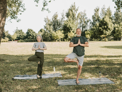 A man and a woman doing a yoga pose outdoors