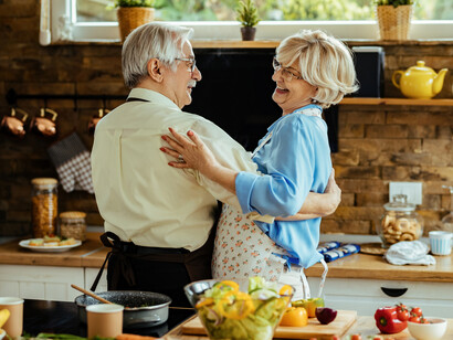 A joyful elderly couple dancing in the kitchen, sharing a quiet moment of happines