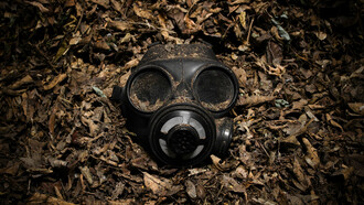 A gas mask among dead leaves represents the futility of ensuring survival through war