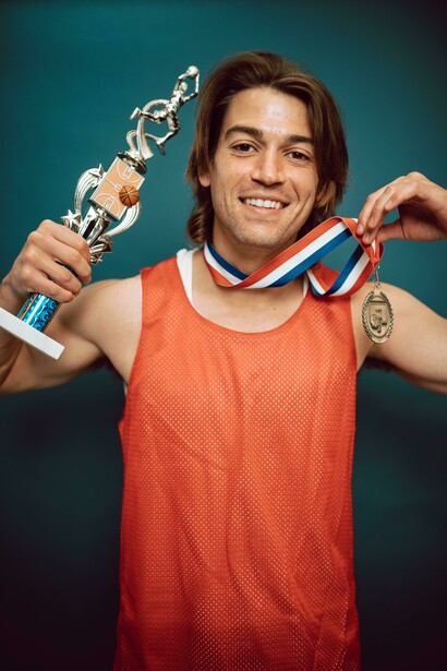 Smiling NBA winner holds a medal and trophy symbolizing personal triumph 