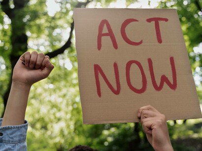 Giovane attivista sui temi ambientali con il cartello "Act Now"  (Agiamo ora) 