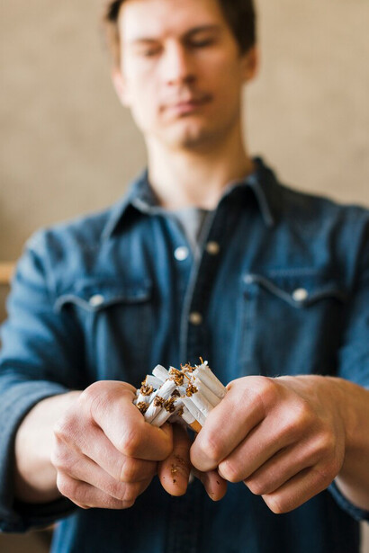 A close-up of a man's hand holding a broken bundle of cigarettes