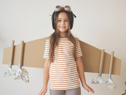 A girl, playfully exploring her dreams with cardboard wings, embodies imagination and the pursuit of success