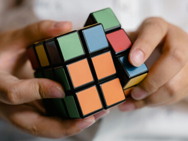 Ce garçon jouant avec le cube Rubik symbolise la manière dont les artefacts externes, comme le Rubik’s Cube, peuvent étendre et modifier les capacités cognitives dans un système cerveau-corps-environnement
