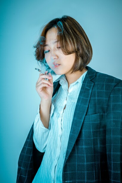 A person wearing a blue blazer smoking a cigarette 