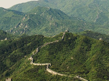 Vista ampla da Muralha da China acompanhando as curvas das montanhas. A imagem evoca a longa trajetória histórica mencionada no artigo e os processos de ascensão, transformação e renovação das sociedades