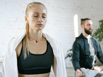 Two individuals immerse themselves in meditation, eyes closed, cultivating inner peace and clarity, a practice that not only enhances focus but also supports health and well-being