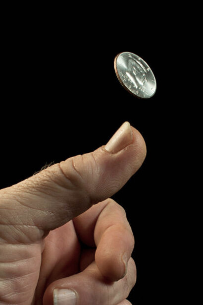 A hand flipping a coin in mid-air, symbolising humanity’s uncertain future