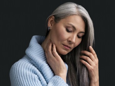 A woman holding her naturally gray hair, symbolizing the acceptance of hair as a reflection of life's experiences