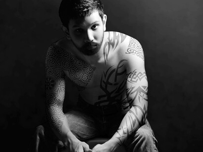 A tattooed man looking confused but feeling alive in the midst of his problems