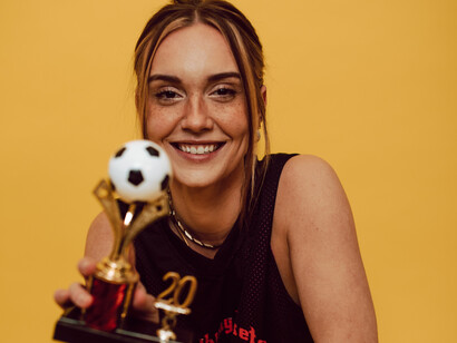 A woman with a soccer trophy win
