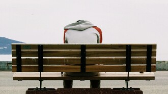 Depressed man sits on a public bench