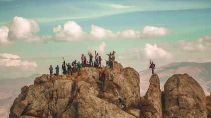 Hikers on a mountain trail, pushing toward the summit, symbolize the determination and perseverance needed to overcome the struggles of entrepreneurship and reach the peak of coaching success