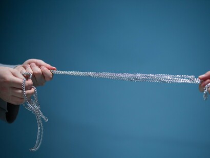 Hands pulling a silver chain in opposite directions, symbolising the emotional tug-of-war between holding on and letting go