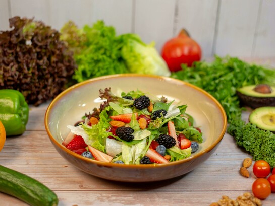 A vibrant vegetable salad presented in an earthy brown ceramic bowl