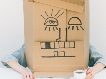 The woman covers her entire head with a cardboard head