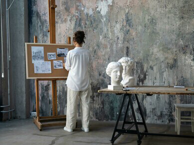 An artist works in an art studio, sculpting in natural light