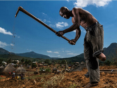 Barrio Chiuijo, Mozambique, Bonifacio Mazin trabajando su campo de verduras con perfecto equilibrio a pesar de perder una de sus piernas a causa de una mina. Fotografía Brent Stirton 