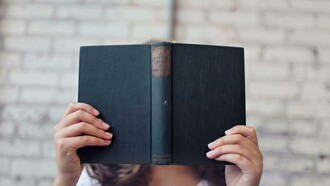Mulher com livro aberto em frente ao rosto. Primeiro de tudo, vamos deixar claro: sim, qualquer leitura ajuda! E não, isso não é uma desculpa para se entupir de revistas de fofoca e achar que está tudo bem (apesar de que, se isso te faz feliz, quem sou eu para julgar?). O ponto é que ler, independentemente do que seja, ativa o cérebro, melhora o vocabulário e a compreensão, além de nos transportar para outros mundos e nos fazer enxergar as coisas de outra maneira