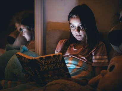 A child reading intently at night, symbolising how books can illuminate young minds even in the darkest moments