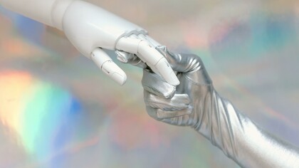 A gloved hand holding a robotic hand 