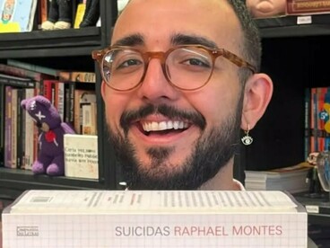 Raphael Montes posa diante de sua biblioteca pessoal, cercado por livros e referências de seu universo profissional. A presença constante da literatura acompanha sua atuação também como roteirista e produtor de narrativas para as telas