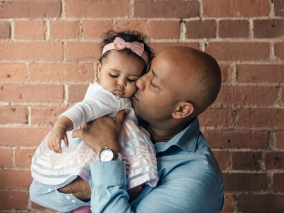 A godfather kissing the goddaughter on the cheek with the appropriate love and tenderness 