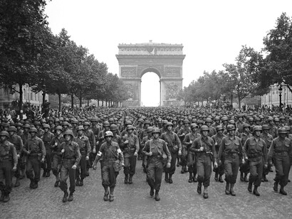 Soldados estadounidenses marchan a lo largo de los Campos Elíseos, con el Arco del Triunfo al fondo, cuatro días después de la liberación de París, Francia