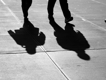 Silhouettes drift along the evening sidewalk, fading into the twilight