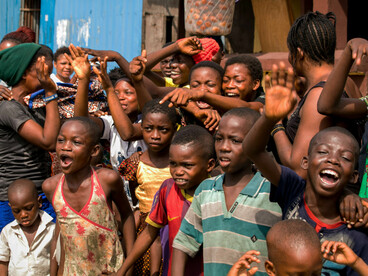 A group of African children pose for a photo in a setting marked by poverty and limited access to adequate nutrition
